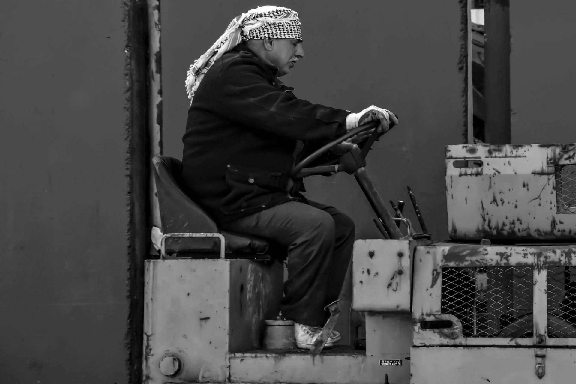 Operador de empilhadeira em ambiente industrial, em imagem preto e branco.