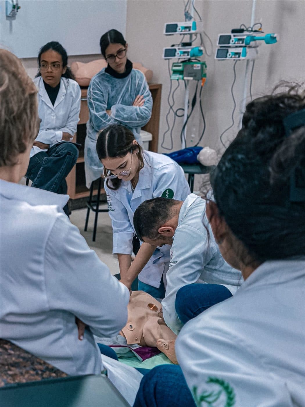 Equipe médica treina reanimação cardiopulmonar em um manequim, coletando dados clínicos durante a simulação.
